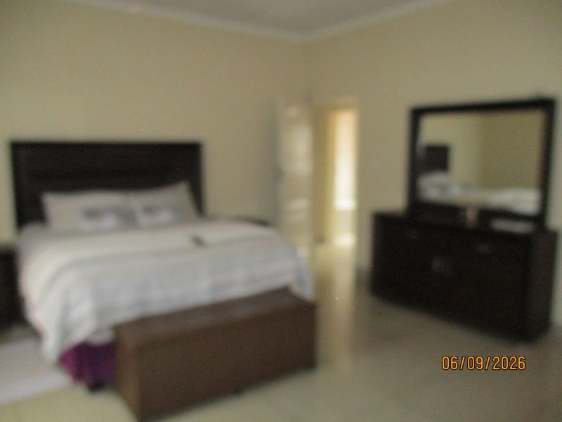 A bedroom interior featuring neutral wall finishes and tiled flooring.