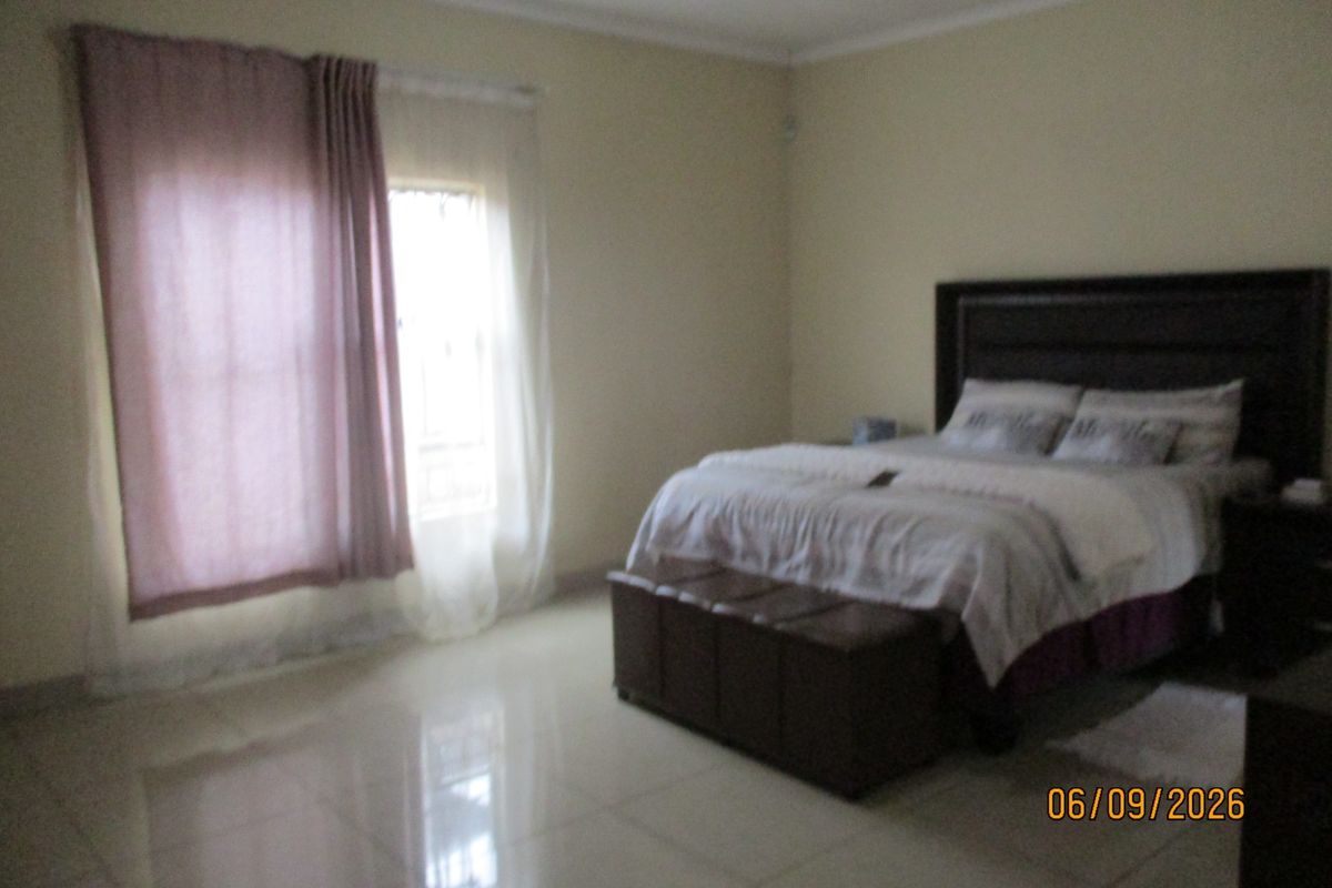 A spacious bedroom featuring neutral wall tones and polished tiled flooring, providing a clean and functional living space.