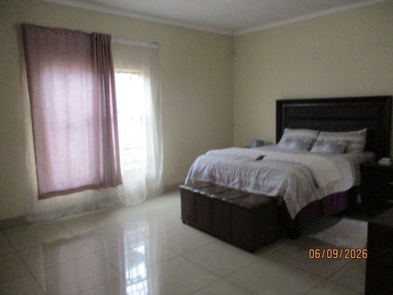 A spacious bedroom featuring neutral wall tones and polished tiled flooring, providing a clean and functional living space.