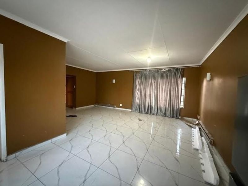 Spacious living area featuring large format marble-look floor tiles, neutral wall finishes, and integrated wall lighting, offering a blank canvas for interior design.
