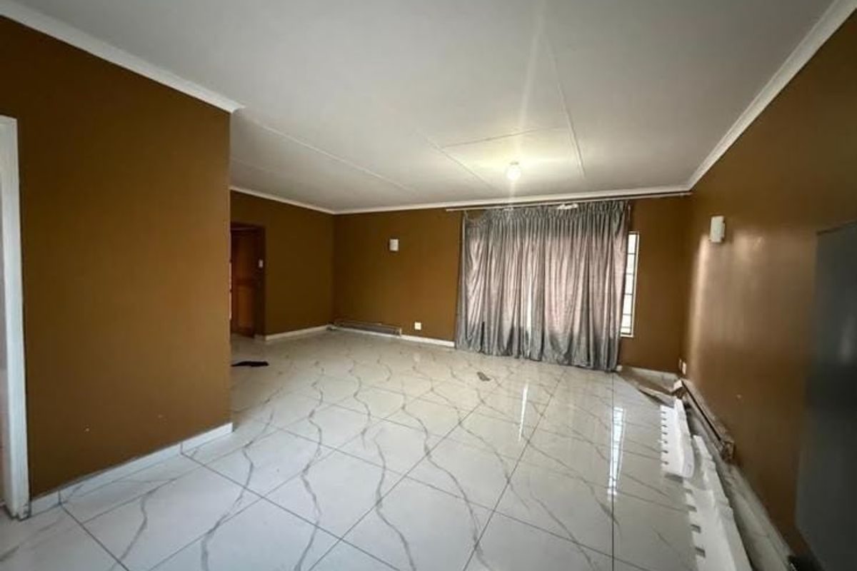 Spacious living area featuring large format marble-look floor tiles, neutral wall finishes, and integrated wall lighting, offering a blank canvas for interior design.