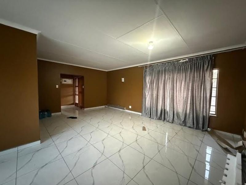 Spacious, empty living room featuring large-format marble-look floor tiles and neutral brown walls, offering a blank canvas for interior design.