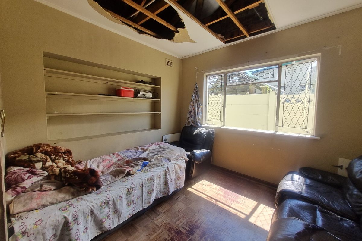 Bedroom featuring parquet flooring and built-in shelving, currently requiring significant ceiling repairs and general renovation to restore the space.
