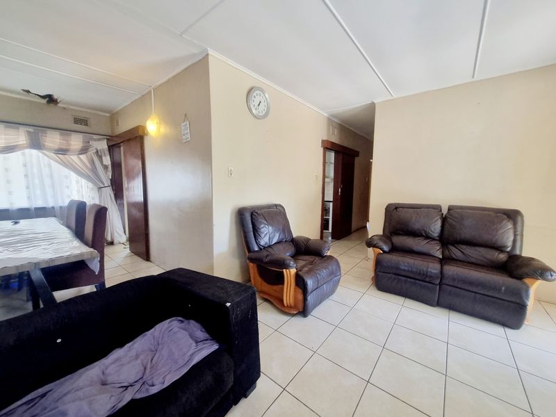 A spacious living area featuring tiled flooring and neutral wall tones, providing a functional layout with access to adjacent rooms.