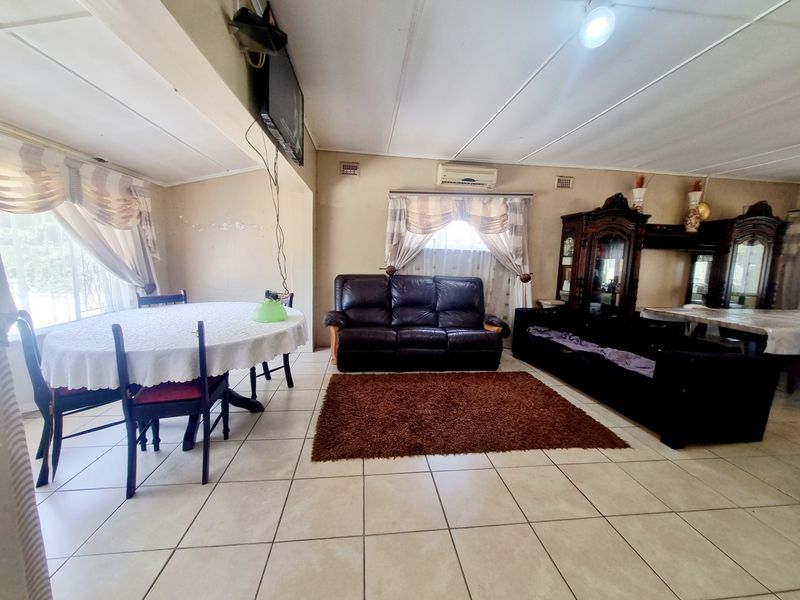 Spacious open-plan living and dining area featuring tiled flooring and a wall-mounted air conditioning unit.