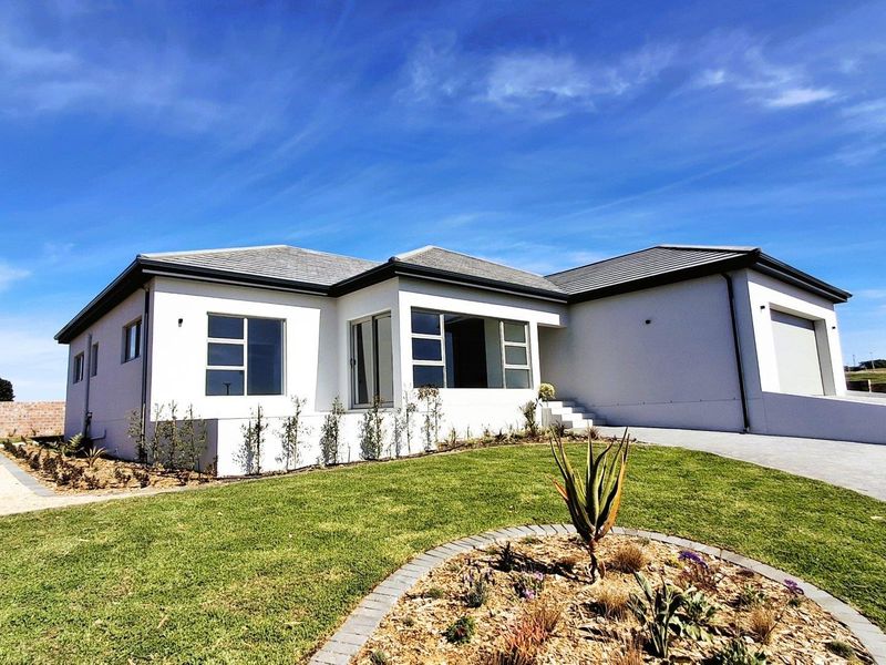 Modern single-story residential home featuring a clean white facade, tiled roof, integrated garage, and well-maintained landscaped front garden.