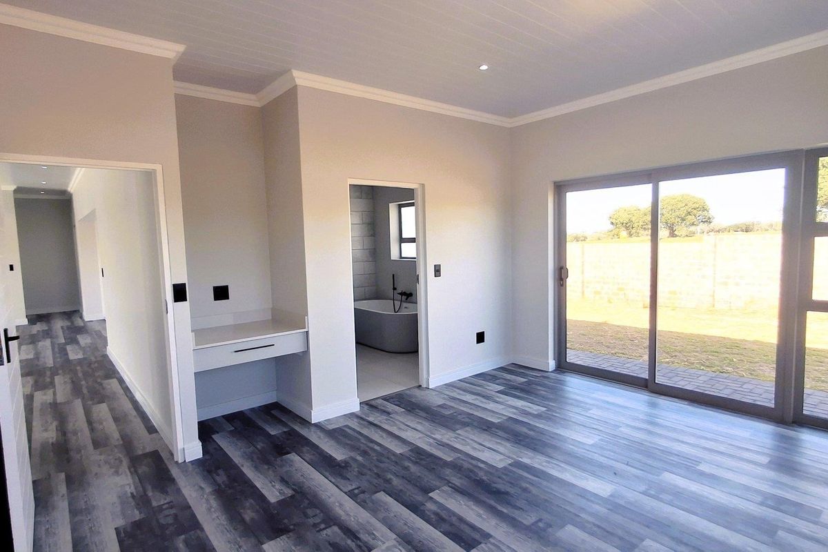 Spacious bedroom featuring modern laminate flooring, built-in vanity, recessed lighting, and large sliding glass doors providing access to the garden.