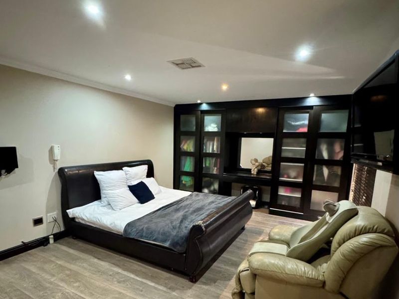 Spacious bedroom featuring modern laminate flooring, recessed downlighting, and a large built-in wardrobe with integrated vanity area.