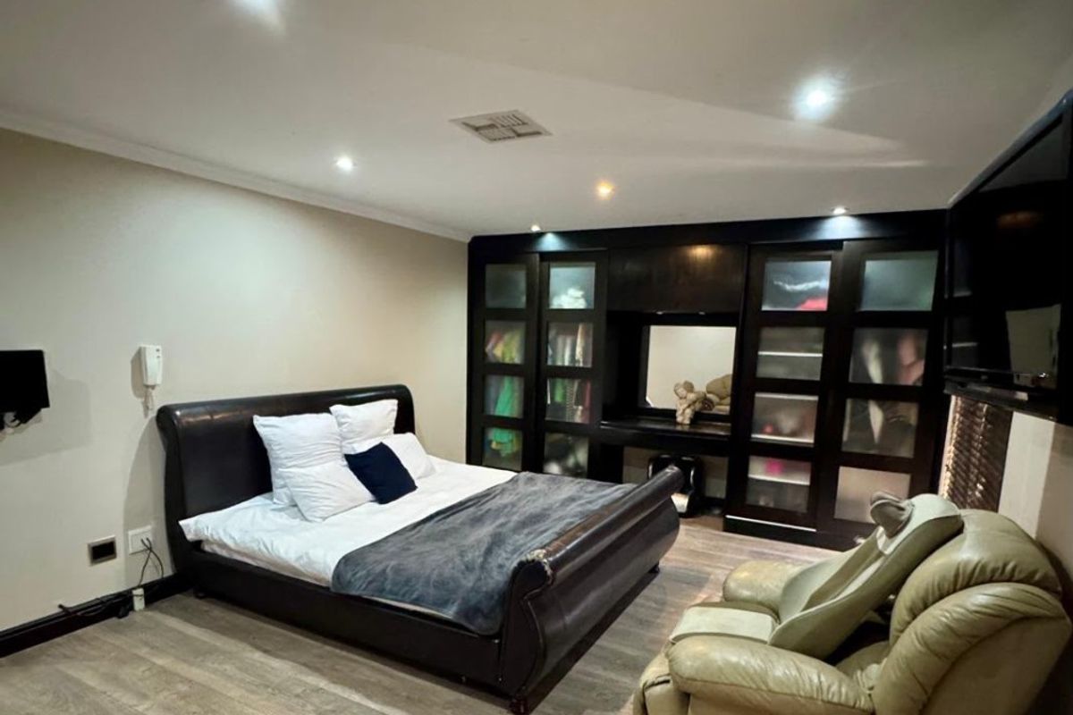 Spacious bedroom featuring modern laminate flooring, recessed downlighting, and a large built-in wardrobe with integrated vanity area.