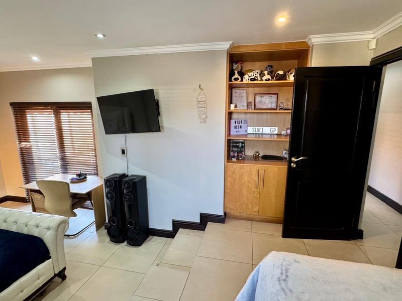 Bedroom featuring tiled flooring, recessed lighting, timber blinds, and a built-in wooden shelving unit with lower cabinet storage.