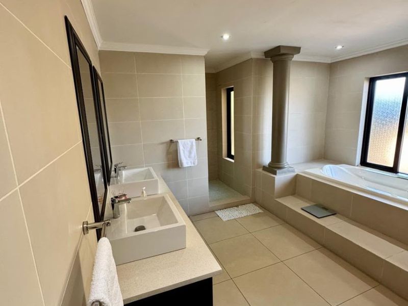 Spacious modern bathroom featuring a double vanity with vessel sinks, a built-in bathtub, and a separate walk-in shower area with neutral tiling.