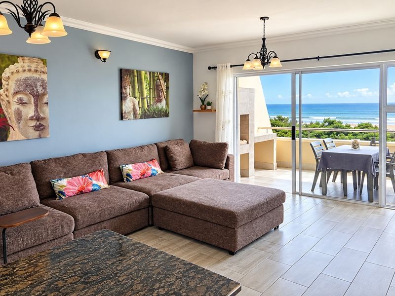 Spacious living room featuring tiled flooring and large sliding glass doors that open onto a balcony with scenic ocean views.