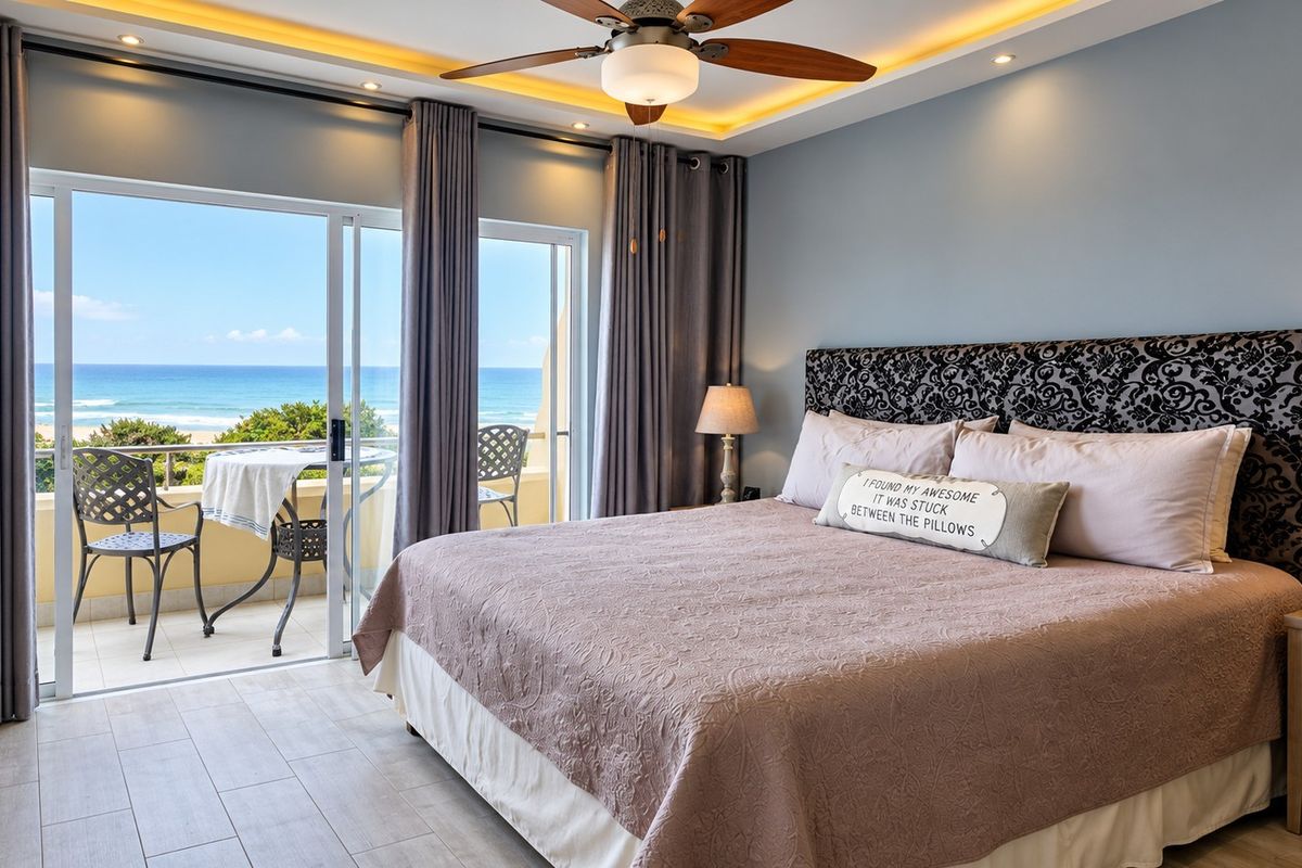 Spacious bedroom featuring modern tiled flooring, recessed ceiling lighting, a ceiling fan, and sliding glass doors opening onto a private balcony with ocean views.
