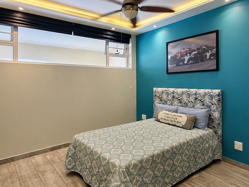 A well-maintained bedroom featuring modern tiled flooring, built-in cupboards, a ceiling fan, and recessed lighting with a vibrant accent wall.