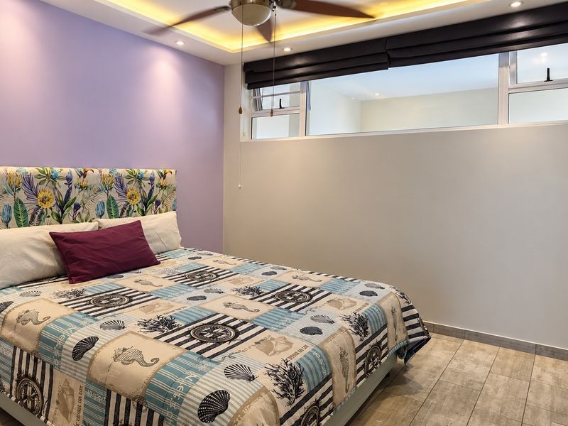 A well-maintained bedroom featuring tiled flooring, recessed cove lighting, a ceiling fan, and a built-in wardrobe with a high-level clerestory window.