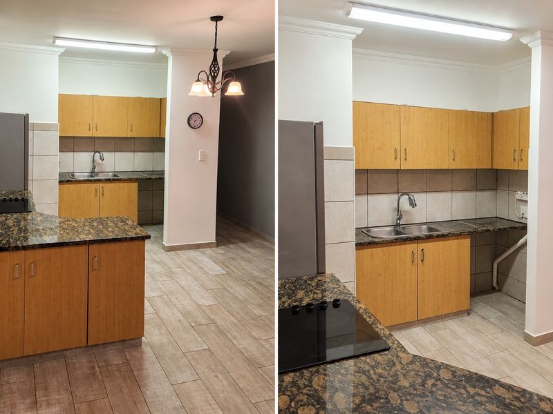 A functional kitchen featuring light wood cabinetry, granite countertops, a double bowl sink, and an electric hob with tiled backsplash and flooring.