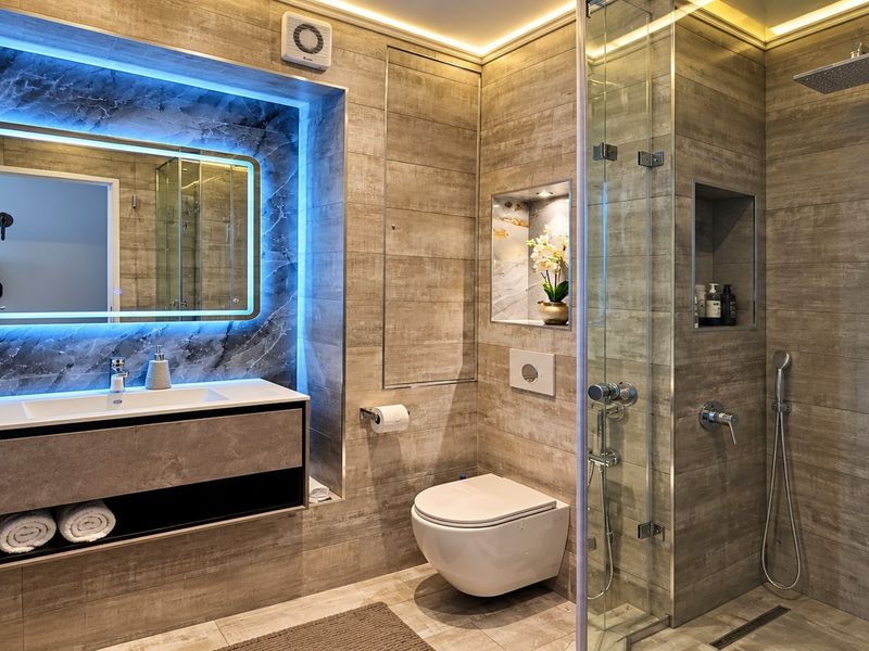 Modern, high-end bathroom featuring a walk-in shower, wall-mounted toilet, sleek vanity with integrated basin, and sophisticated LED ambient lighting.