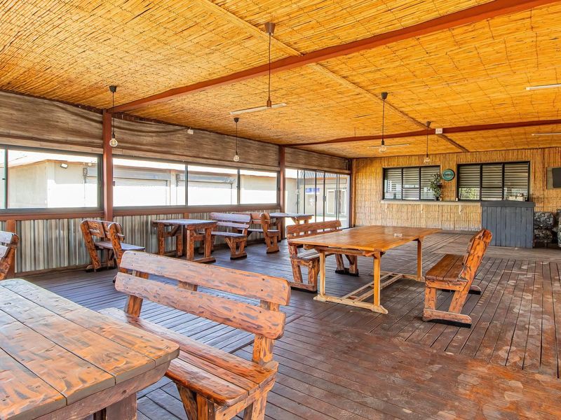 Spacious covered outdoor patio featuring timber decking, a bamboo ceiling, and a built-in bar area, ideal for social gatherings or commercial use.