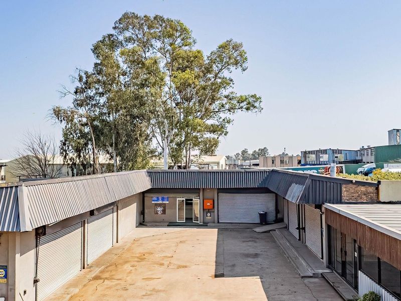 Aerial view of a commercial property courtyard featuring multiple metal roller shutter doors and a paved yard area.