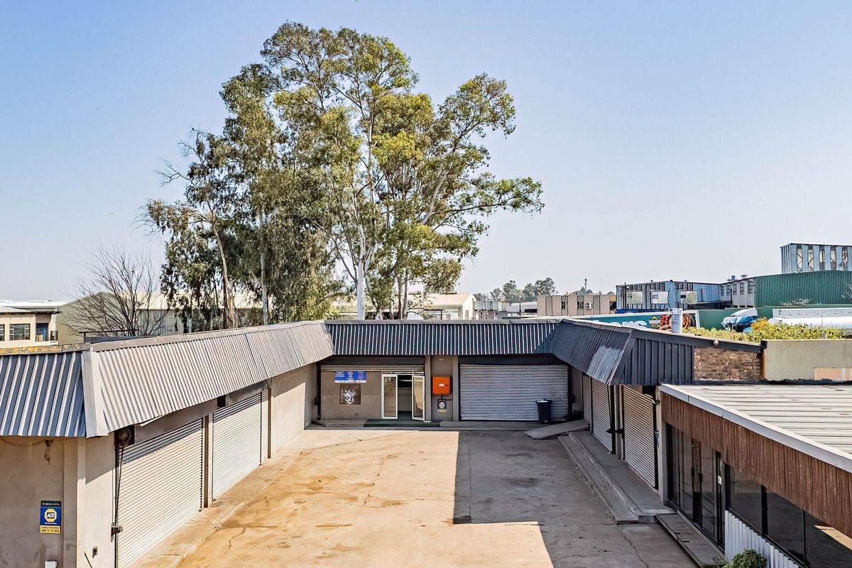 Aerial view of a commercial property courtyard featuring multiple metal roller shutter doors and a paved yard area.