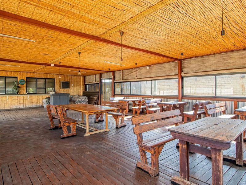 Spacious covered outdoor patio featuring timber decking, bamboo ceiling and wall cladding, and large sliding windows, suitable for retail or hospitality use.