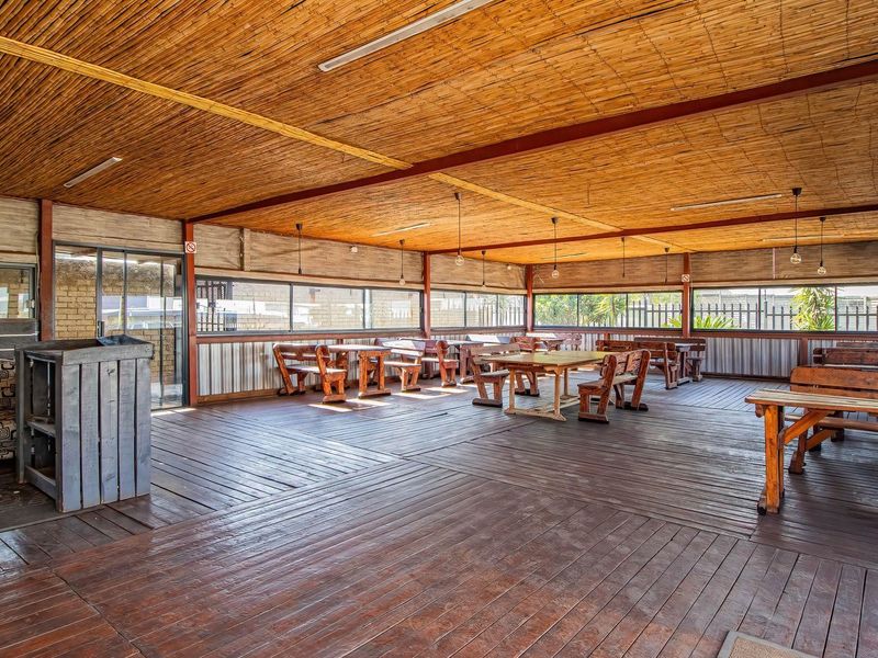 Spacious covered outdoor patio area featuring timber decking, a bamboo ceiling, and large sliding glass doors, suitable for retail or hospitality use.