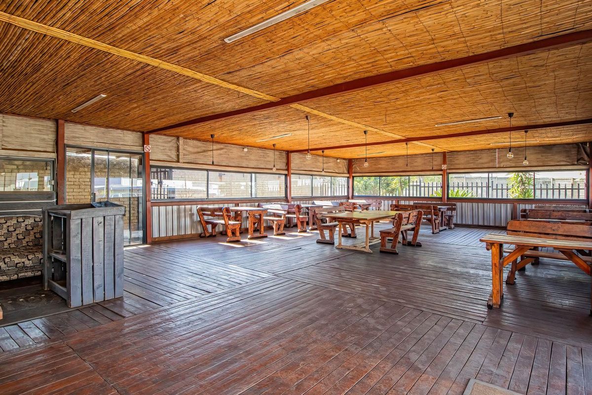 Spacious covered outdoor patio area featuring timber decking, a bamboo ceiling, and large sliding glass doors, suitable for retail or hospitality use.