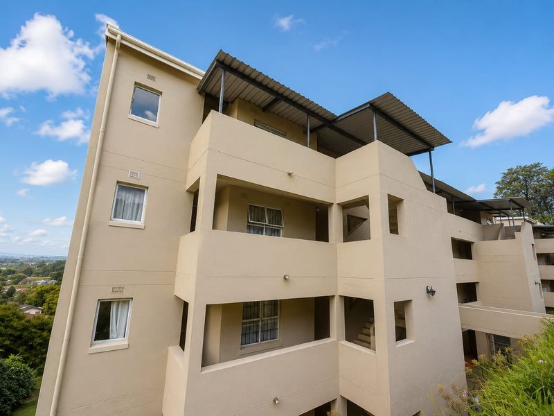 Exterior view of a multi-story apartment building featuring stacked balconies, metal roofing, and neutral facade finishes.