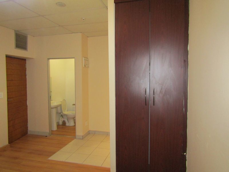 A bedroom featuring laminate flooring, a built-in wardrobe, and an attached en-suite bathroom with tiled flooring.