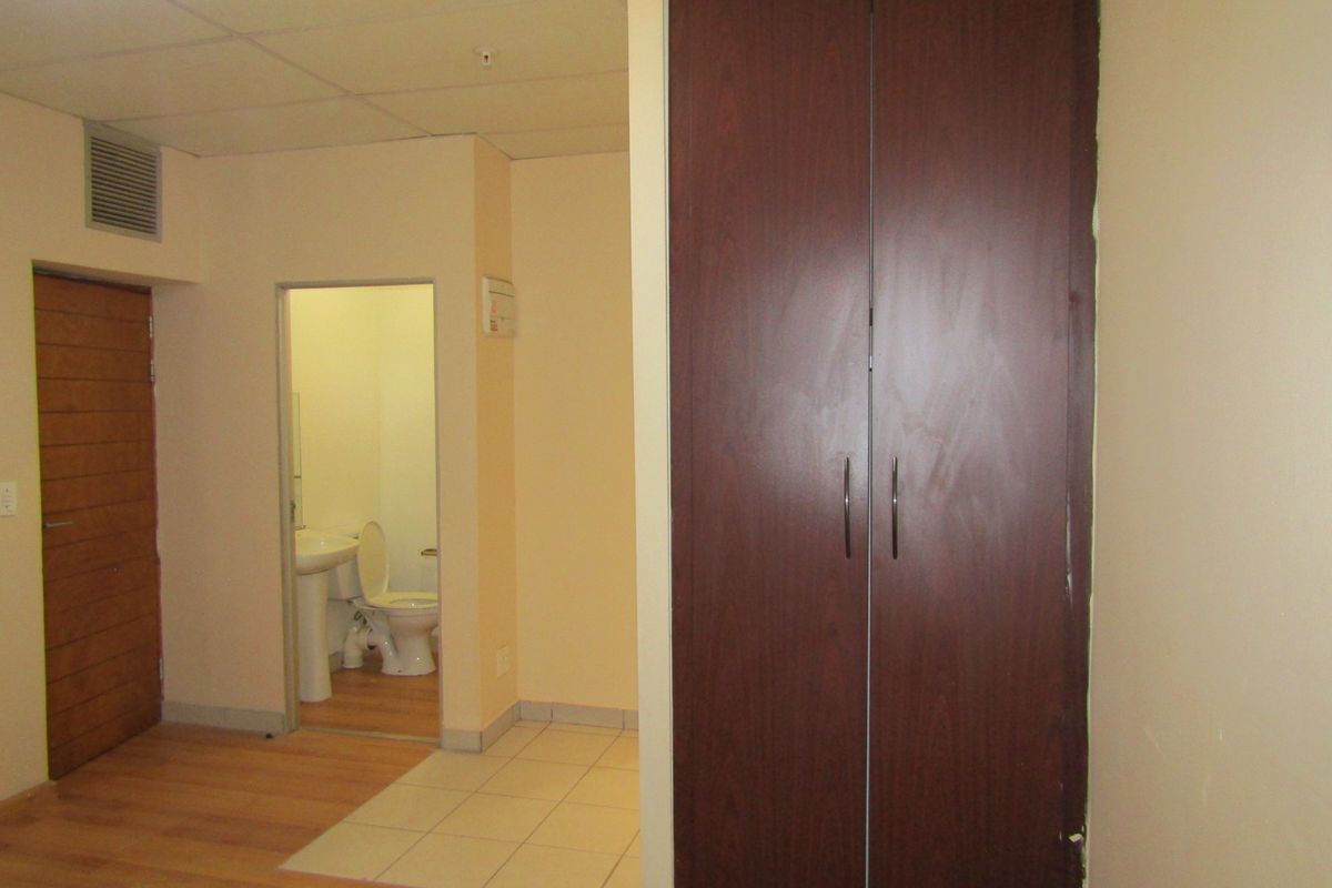 A bedroom featuring laminate flooring, a built-in wardrobe, and an attached en-suite bathroom with tiled flooring.