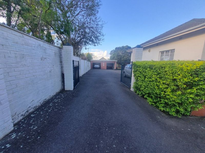 A paved driveway leading to a detached garage, featuring a secure gated entrance and established boundary walling.