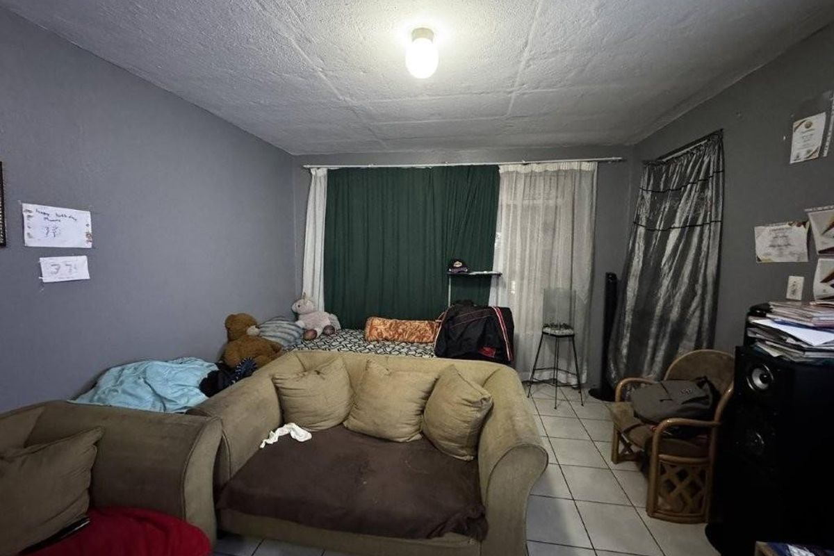 A living room area featuring tiled flooring and a standard ceiling light fixture, requiring cosmetic updates to improve the overall aesthetic.