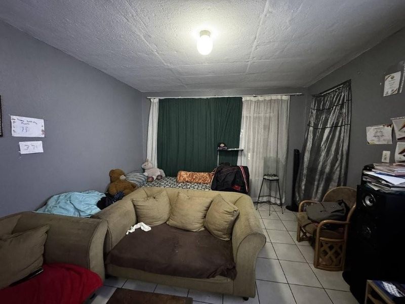 A living room area featuring tiled flooring and a standard ceiling light fixture, requiring cosmetic updates to improve the overall aesthetic.