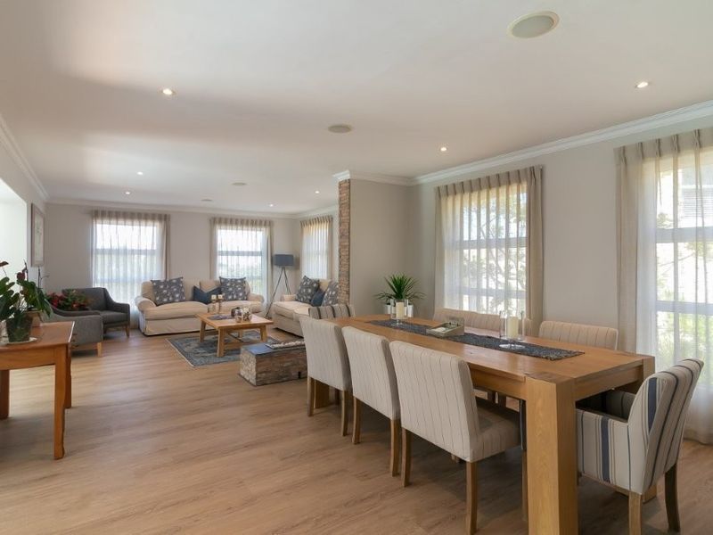Spacious open-plan living and dining area featuring modern laminate flooring, recessed lighting, and a decorative exposed brick pillar.