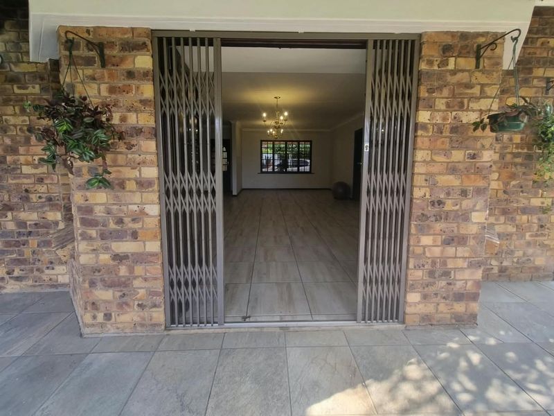 Entrance view of a townhouse featuring a brick facade, security gate, and tiled flooring leading into an open-plan living area.