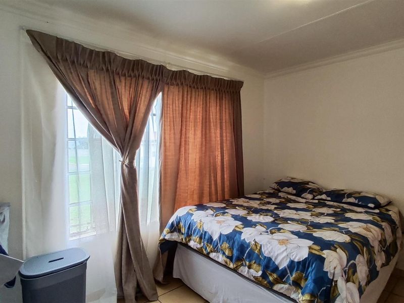 A functional bedroom featuring tiled flooring and window curtain rails, offering a neutral space ready for personalization.