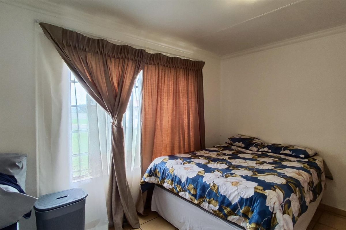 A functional bedroom featuring tiled flooring and window curtain rails, offering a neutral space ready for personalization.