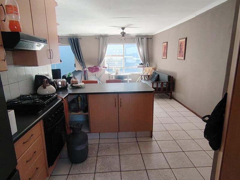 Open-plan kitchen and living area featuring tiled flooring, built-in cabinetry, a gas stove, and a breakfast counter, offering a functional layout.