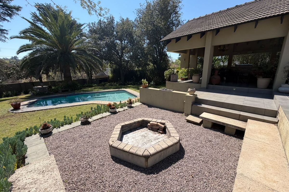 Rear garden area featuring a swimming pool, covered patio, and a central built-in stone fire pit with gravel landscaping.