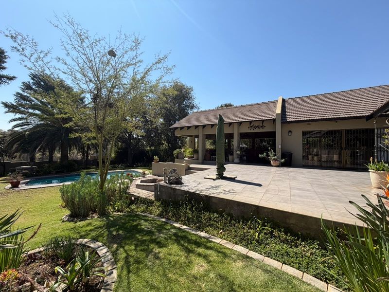 Spacious rear exterior featuring a large tiled patio, swimming pool, and well-maintained garden area, ideal for outdoor entertaining.