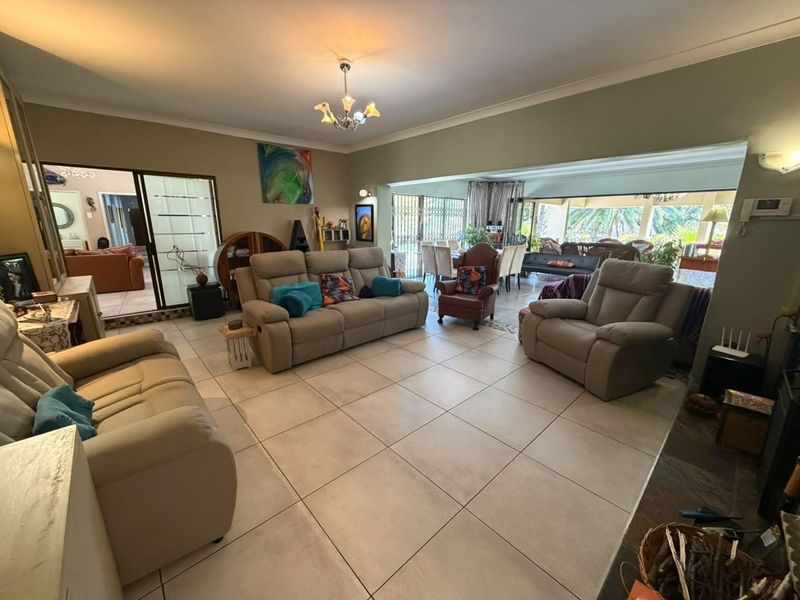 Spacious open-plan living area featuring large format floor tiles, neutral walls, and seamless flow to the outdoor patio through sliding glass doors.