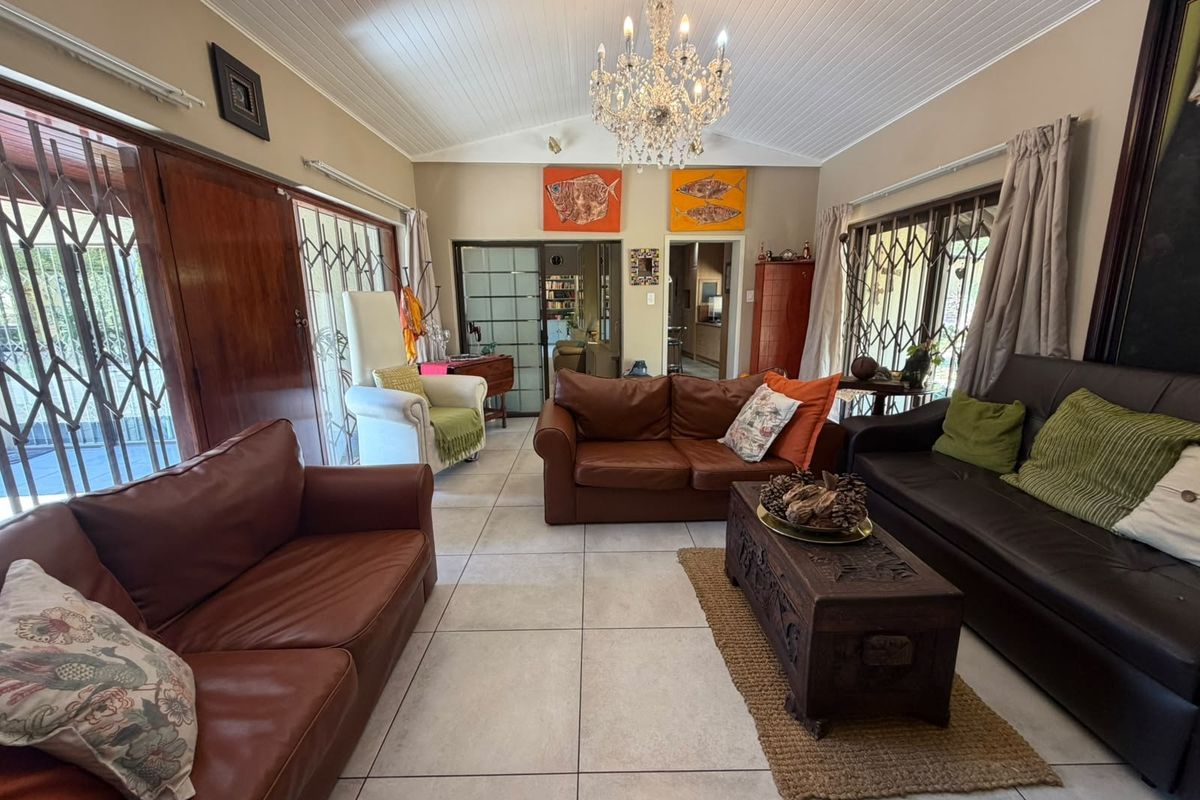 Spacious living room featuring a vaulted tongue and groove ceiling, tiled flooring, and large sliding glass doors with security gates leading to the exterior.