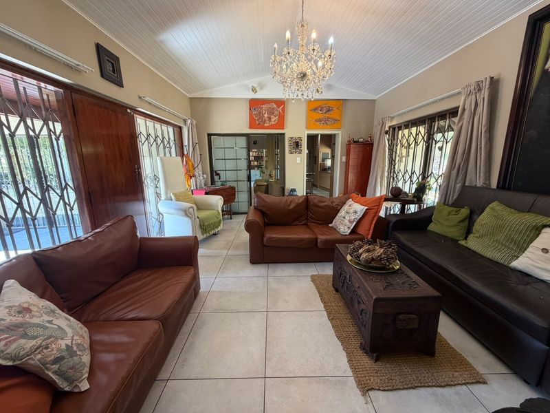 Spacious living room featuring a vaulted tongue and groove ceiling, tiled flooring, and large sliding glass doors with security gates leading to the exterior.