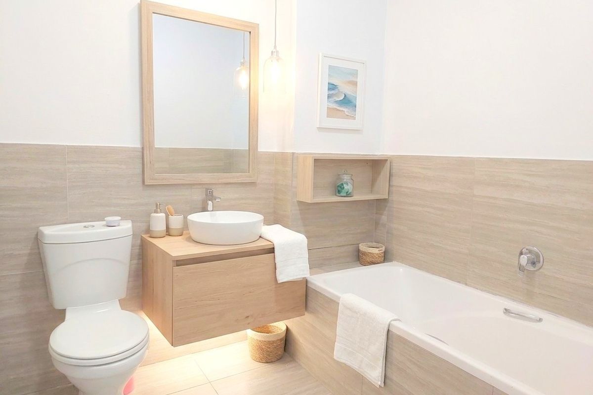Modern bathroom featuring a wall-mounted vanity with a vessel sink, a built-in bathtub, and neutral-toned wall and floor tiling.