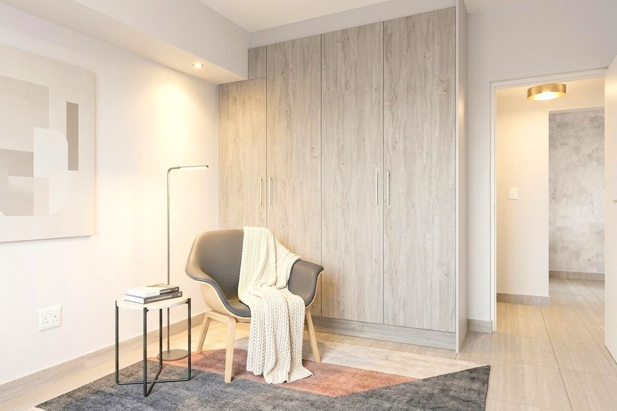 A modern bedroom featuring light wood-grain built-in wardrobes, neutral tiled flooring, and recessed ceiling lighting.