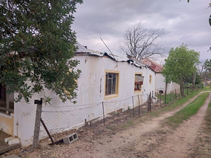 Exterior view of a property showing significant structural damage to the roof and exterior walls, requiring extensive renovation or redevelopment.