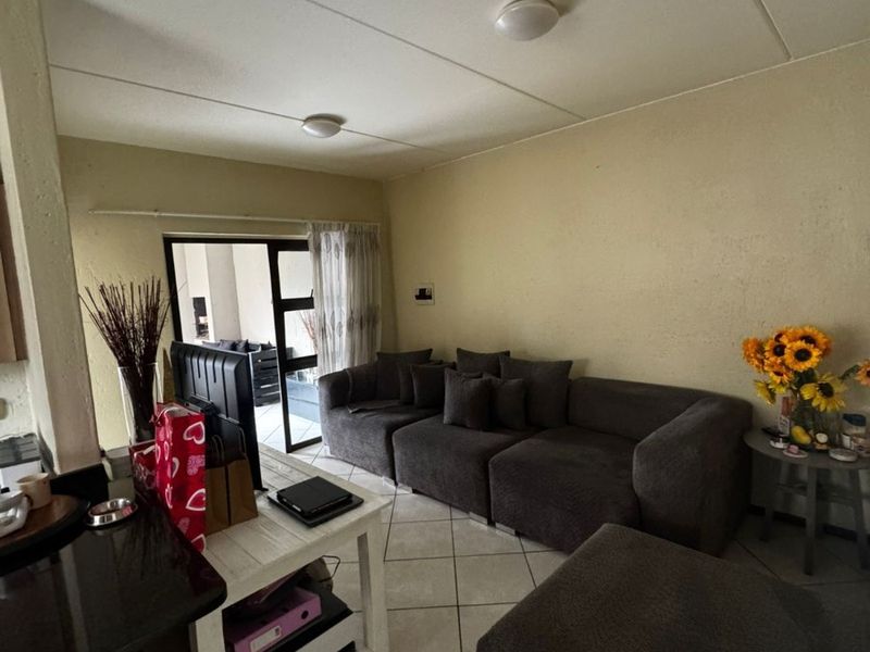 Open plan living area featuring tiled flooring and a sliding glass door leading to an outdoor space, with neutral wall finishes.