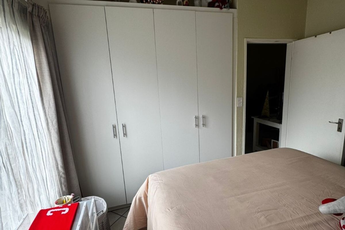 A bedroom featuring a large white built-in wardrobe and tiled flooring, providing functional storage space.