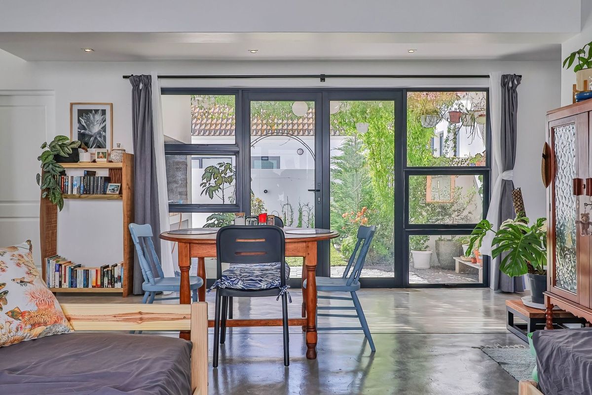 A bright living area featuring polished concrete floors and large aluminium-framed glass doors providing direct access to the rear garden.