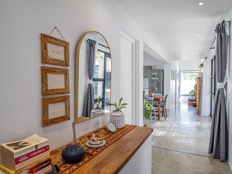 A bright, modern hallway featuring polished concrete floors and recessed lighting, leading through to an open-plan living area.